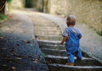 Boy (14-16 months) climbing stone stairway, rear view